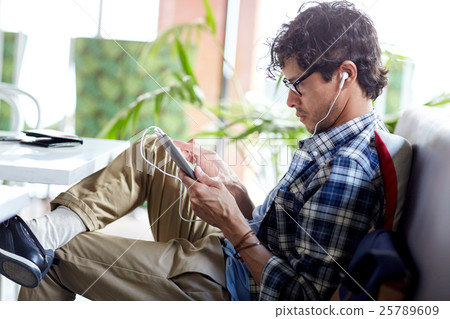 man with tablet pc and earphones sitting at cafe man with tablet pc and earphones sitting at cafe 25789609