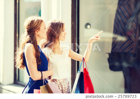 happy women with shopping bags at shop window 25789723