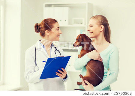 happy woman with dog and doctor at vet clinic 25790862