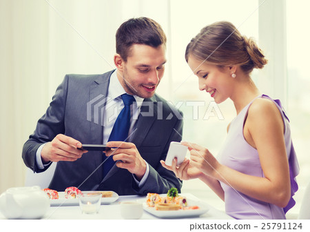 smiling couple with sushi and smartphones smiling couple with sushi and smartphones 25791124