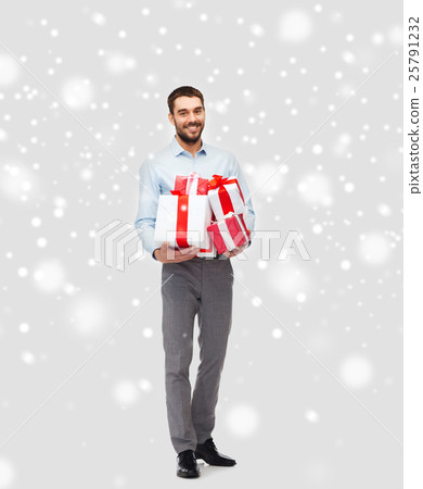 happy young man holding christmas gifts over snow 25791232