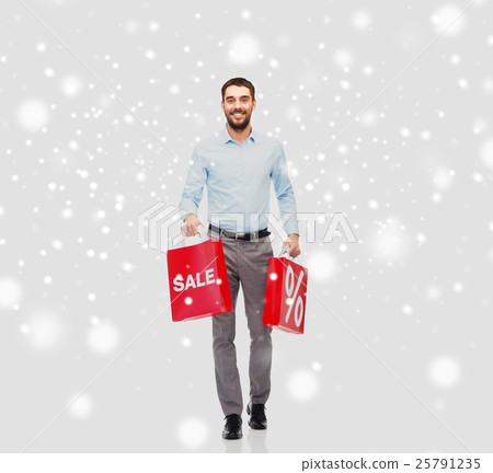 smiling man with red shopping bags over snow smiling man with red shopping bags over snow 25791235