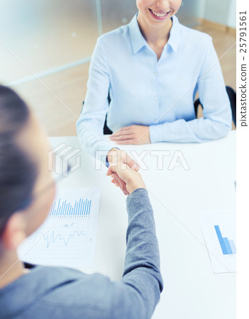 two smiling businesswoman shaking hands in office 25791561