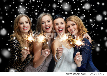 happy young women with sparklers over snow 25791717