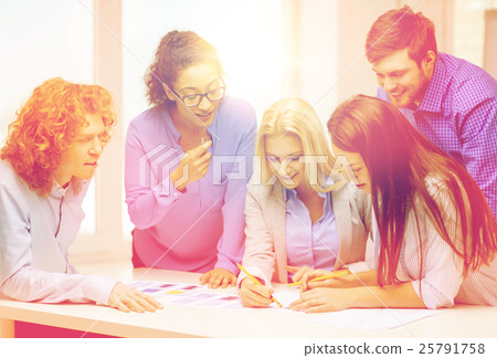 smiling creative team looking over clothes designs smiling creative team looking over clothes designs 25791758