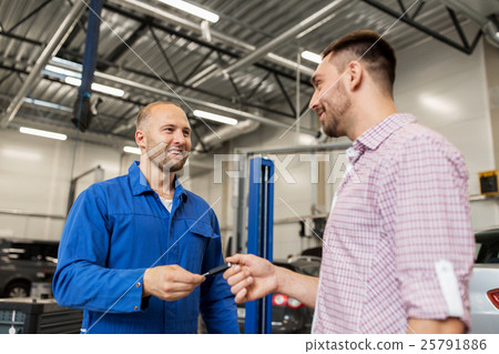 auto mechanic giving key to man at car shop 25791886