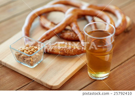 close up of beer, pretzels and peanuts on table 25792410