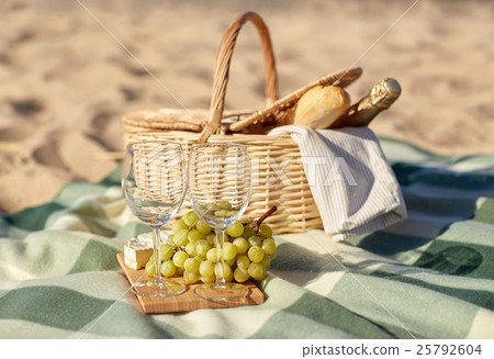picnic basket with wine glasses and food on beach 25792604