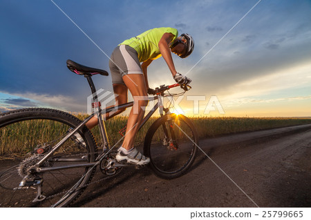 Biker on the meadow at the sunset against blue sky 25799665