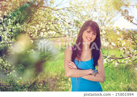 Woman smiling standing in blooming trees in spring 25801994