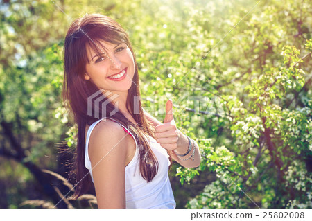 Happy woman gesturing thumb up outdoors Happy woman gesturing thumb up outdoors 25802008
