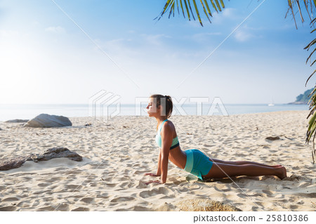 Young pretty slim brunette woman practise yoga pose tropical beach 25810386
