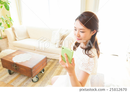 看智能手機的婦女在屋子裡 看智能手機的婦女在屋子裡 25812670