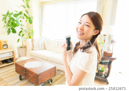 看智能手機的婦女在屋子裡 看智能手機的婦女在屋子裡 25812671