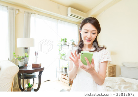 看智能手機的婦女在屋子裡 看智能手機的婦女在屋子裡 25812672