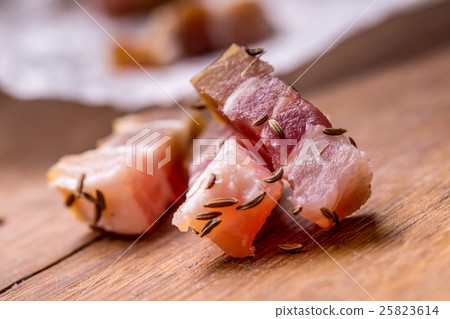 Raw smoked bacon slices on wooden board with cumin 25823614