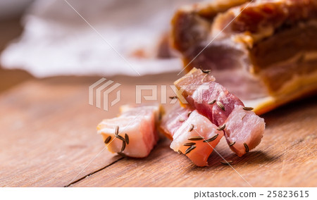 Raw smoked bacon slices on wooden board with cumin Raw smoked bacon slices on wooden board with cumin 25823615