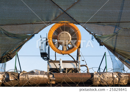 Mounted on the fence industrial fan. 25829841