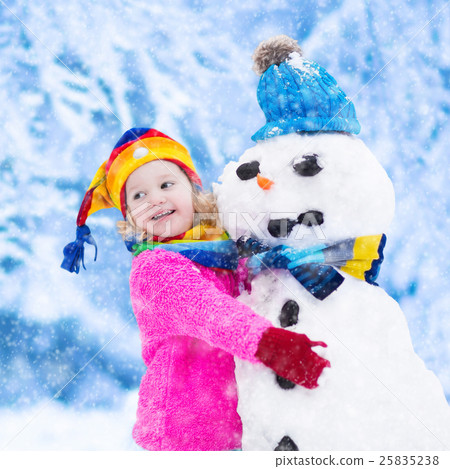 Little girl building a snow man in winter 25835238