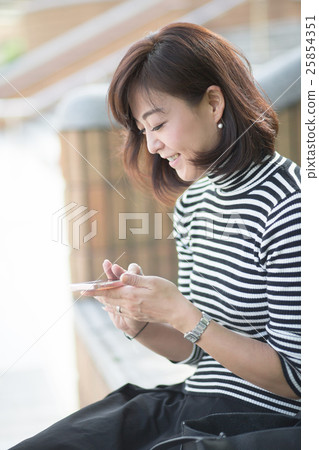 Middle female touching a smartphone outdoors Middle female touching a smartphone outdoors 25854351