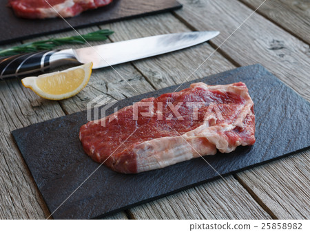 Raw beef steak on dark wooden table background 25858982