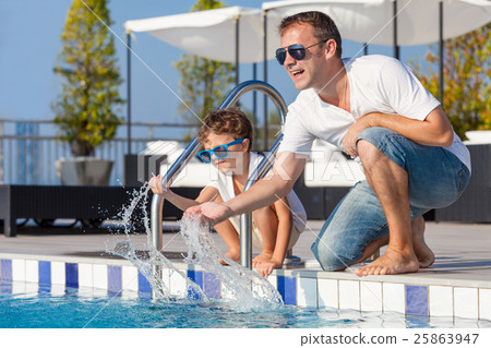 Father and son relaxing near a swimming pool  at the day time. 25863947