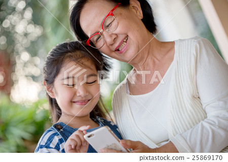 Little Asian girl using mobile phone with grandmom 25869170