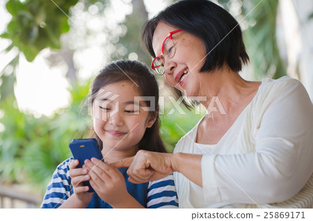 Little Asian girl using mobile phone with grandmom 25869171