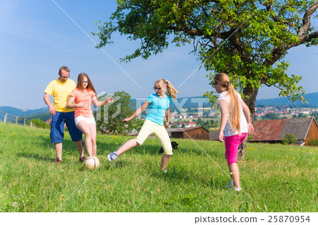 Family playing soccer on meadow in summer Family playing soccer on meadow in summer 25870954
