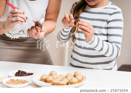 Pregnant mum and her daughter baking together Pregnant mum and her daughter baking together 25871034