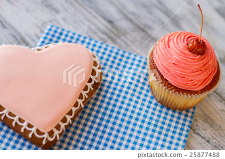 Pink cupcake and heart cookie. Pink cupcake and heart cookie. 25877488