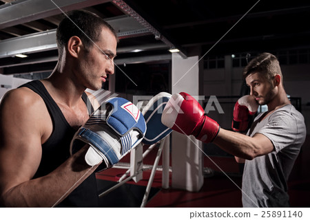 Side view of young boxer training hook on pad Side view of young boxer training hook on pad 25891140