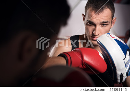Young trainer holding boxing pad Young trainer holding boxing pad 25891143