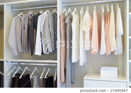 white dress and shirts hanging in white wardrobe 25900867