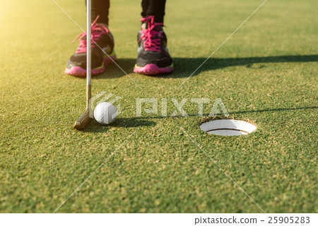 Golf player at the putting green putting golf ball Golf player at the putting green putting golf ball 25905283