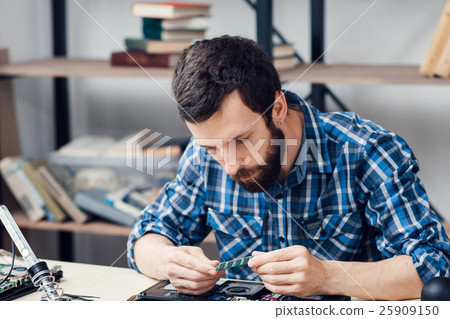 Bearded engineer examing micro circuit 25909150