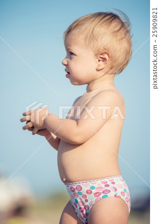 Cute baby playing with toys on sandy beach near 25909821