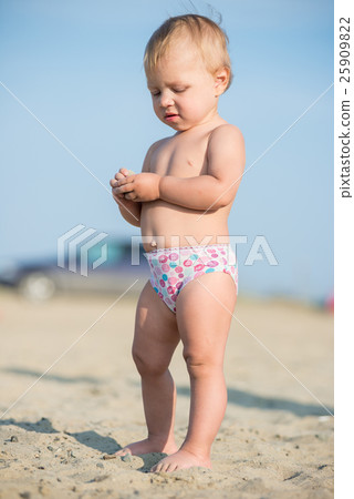 Cute baby playing with toys on sandy beach near 25909822