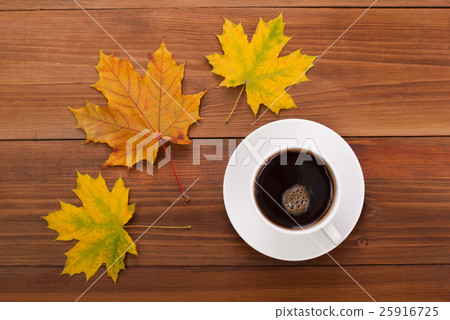Cup of coffee and maple leaves on a wooden table. Cup of coffee and maple leaves on a wooden table. 25916725