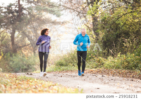 Beautiful senior couple running outside in sunny 25918231