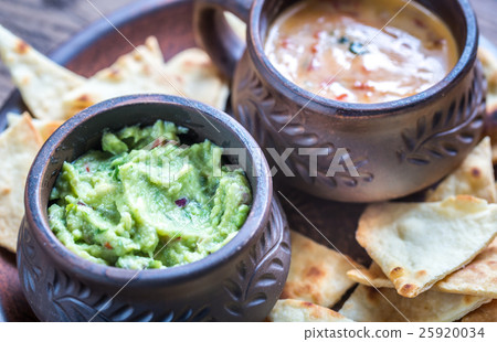 Bowls of guacamole and queso with tortilla chips 25920034