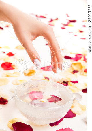 Cropped hand above bowl with petals 25925782