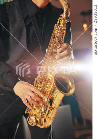 Young man in a suit hold saxophone 25935012