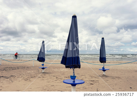 Cyclist and umbrellas on the beach of the Sea Cyclist and umbrellas on the beach of the Sea 25936717