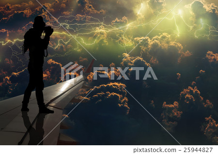 silhouette of man who taking photo of the thunder lightnings over the clouds and storm on airplane wing, Challenge business concept 25944827