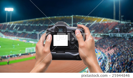 Hand holding the camera over Abstract blurred photo crowd of spectators on a stadium with a football match, sport background concept Hand holding the camera over Abstract blurred photo crowd of spectators on a stadium with a football match, sport background concept 25944846