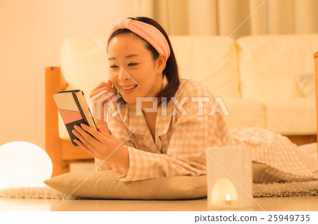 A woman watching a smartphone in a room at night A woman watching a smartphone in a room at night 25949735