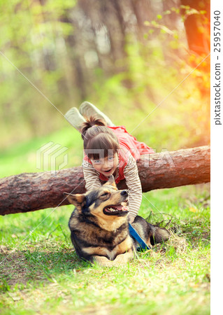 Happy little girl playing with dog in the forest Happy little girl playing with dog in the forest 25957040