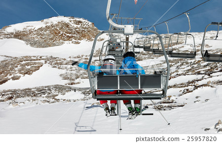 Young couple elevating on chairlift Young couple elevating on chairlift 25957820