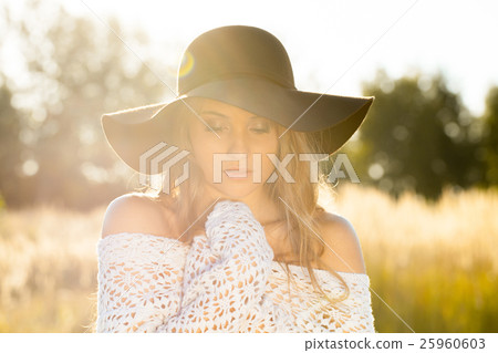 Beautiful young lady posing in a field at sunrise Beautiful young lady posing in a field at sunrise 25960603